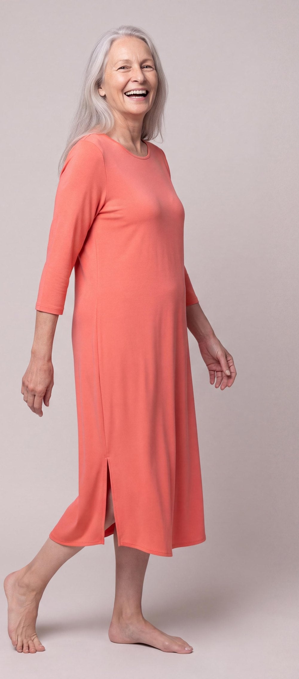 A woman in the DayBasics Long Scoop Neck Nightgown with 3/4 Sleeves in Coral, mid-step and laughing
