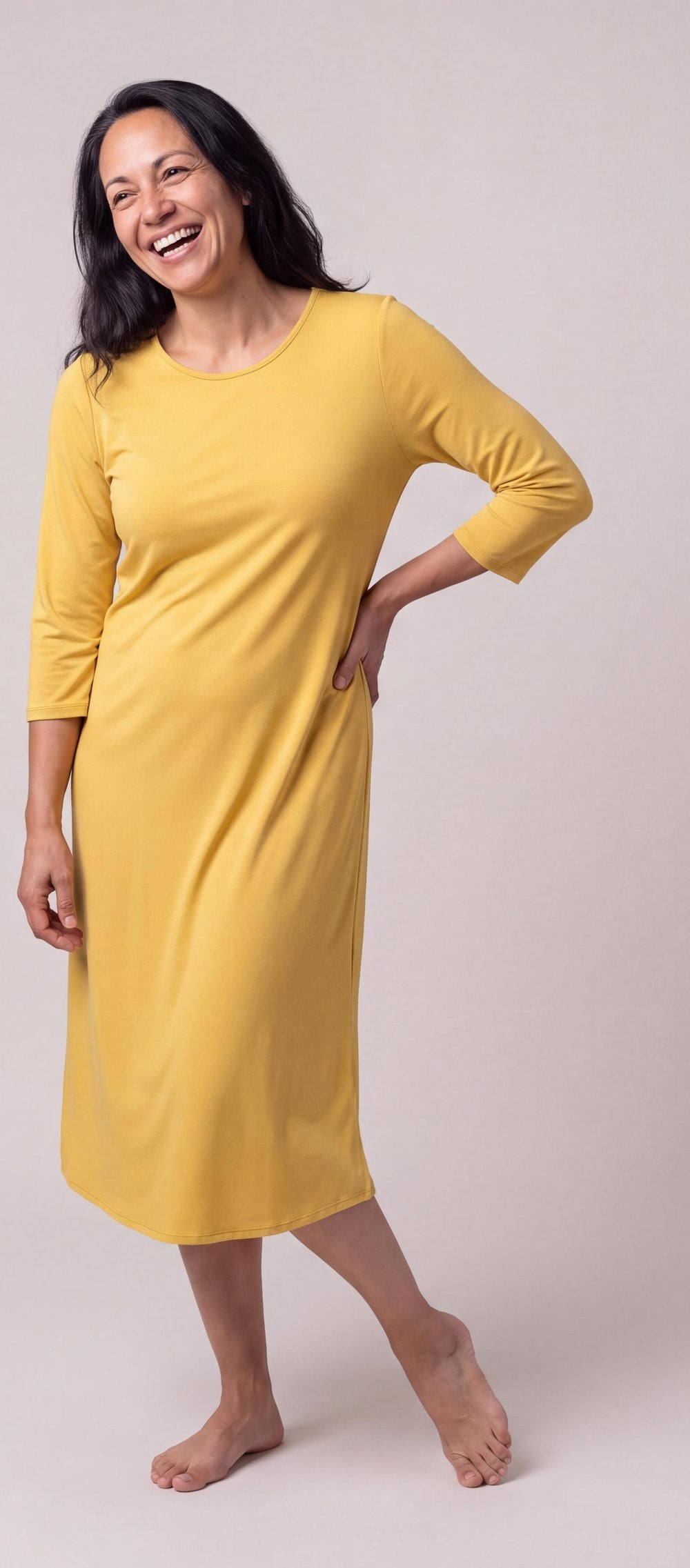 A woman in the DayBasics Long Scoop Neck Nightgown with 3/4 Sleeves in Lemon, laughing, hand on hip