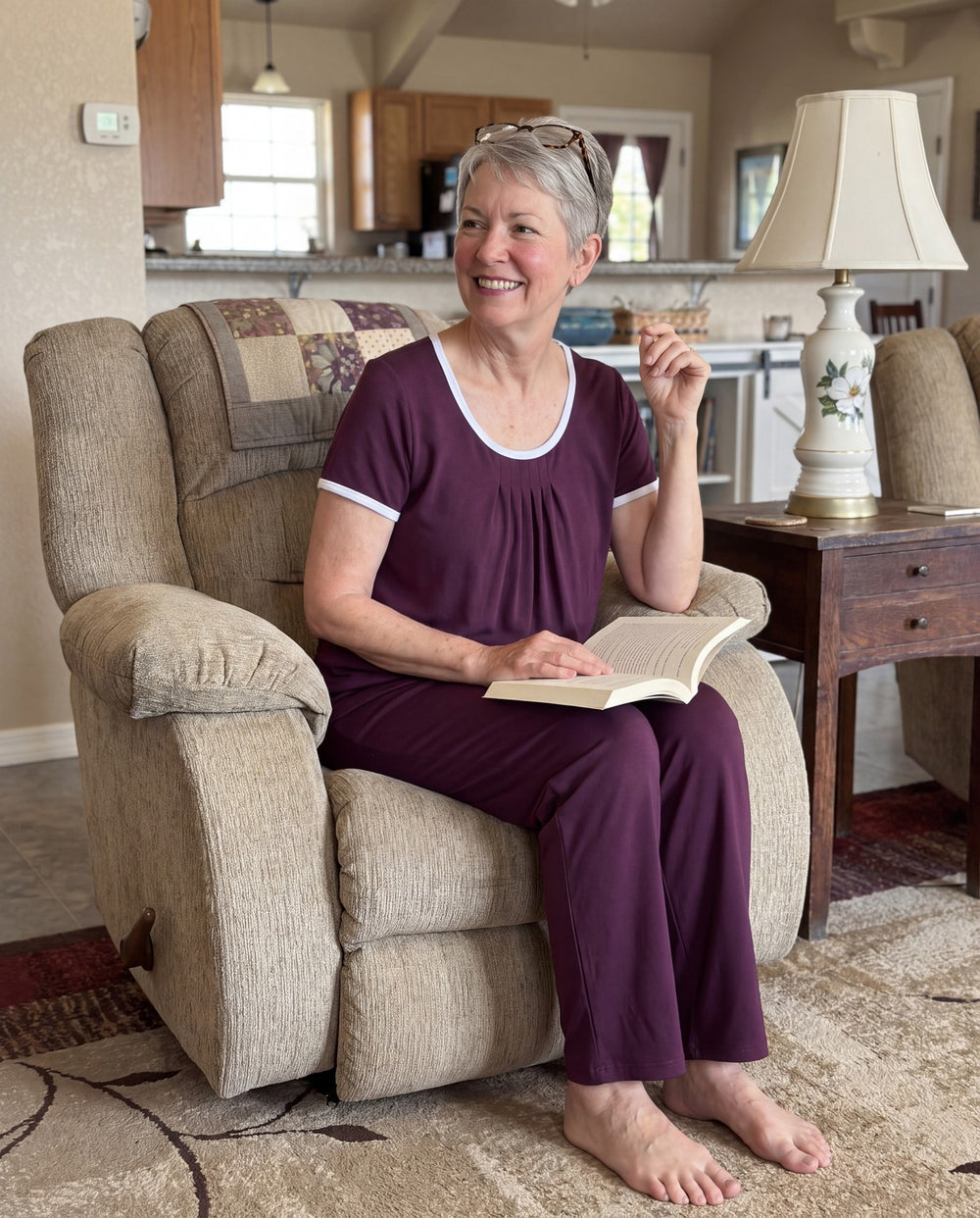 A woman reading in her armchair in the Merlot Cool-jams NightCool Pleated T-Shirt and Pants