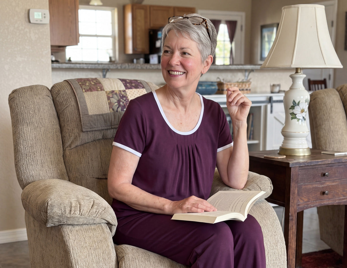 A woman reading in her armchair in the Merlot Cool-jams NightCool Pleated T-Shirt and Pants