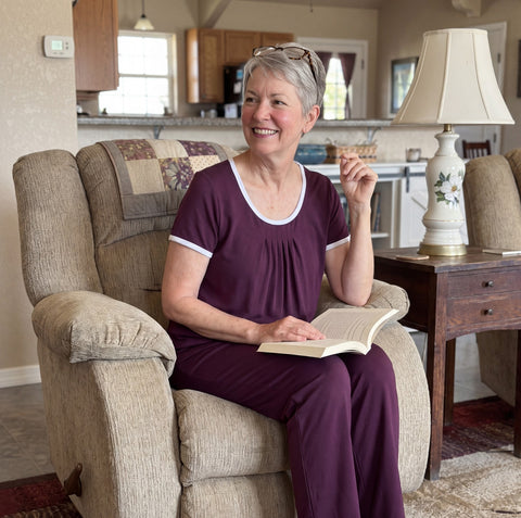 A woman reading in her armchair in the Merlot Cool-jams NightCool Pleated T-Shirt and Pants